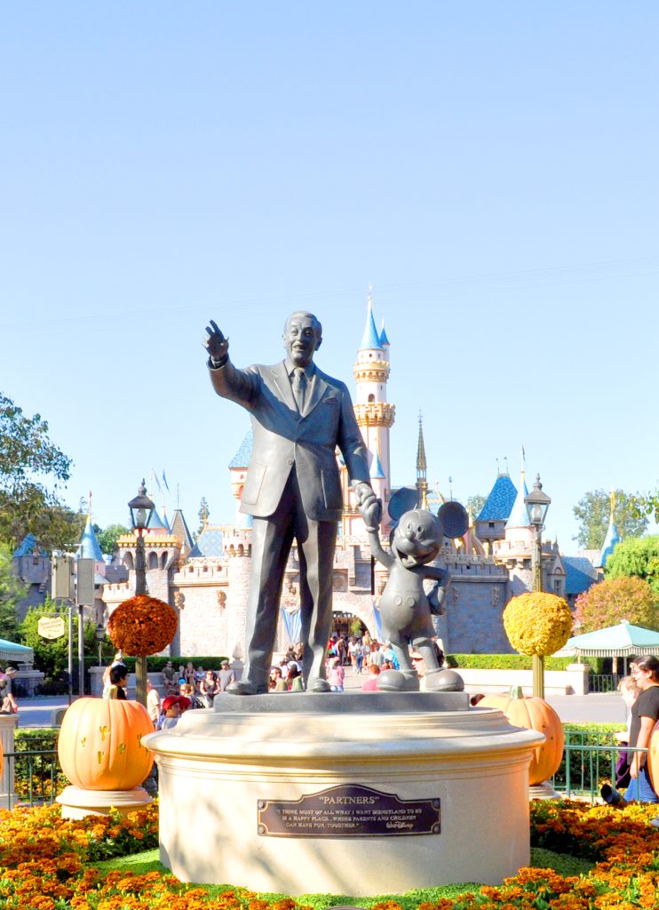 statue of walt disney and mickey mouse in front of disneyland castle