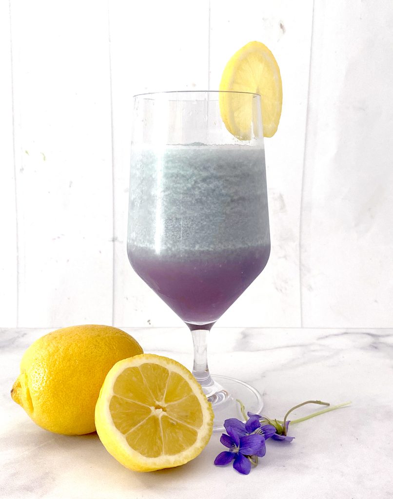 frozen violet lemonade in glass with lemon garnish